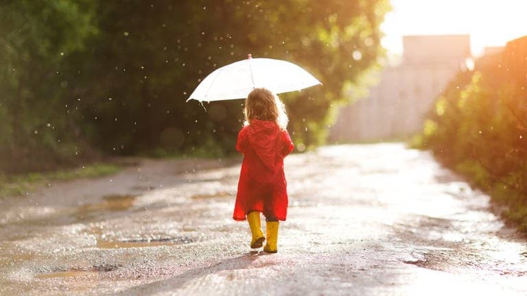 Ein Kind läuft mit Schirm und Gummistiefeln durch den Regen. (Foto: Adobe Stock, ulza)